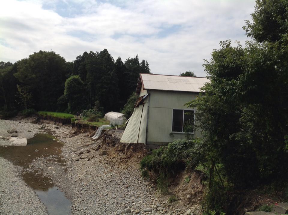 鹿沼市被災状況02、川縁がえぐられ建屋の基礎が一部流される